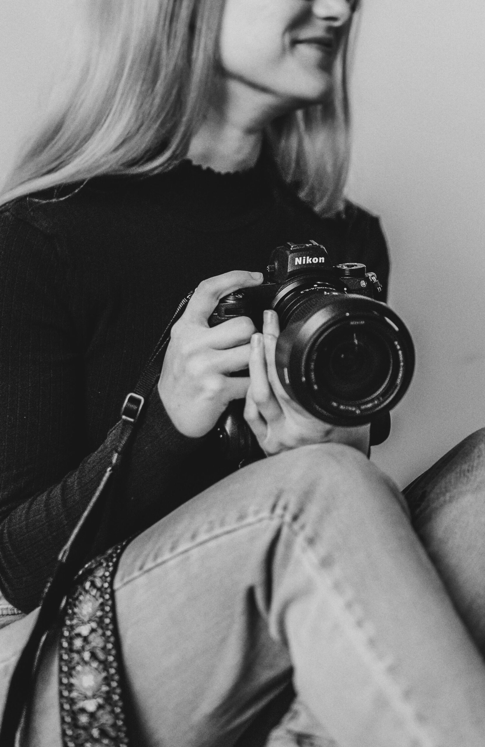 Artistic black and white portrait of a woman holding a professional camera, emphasizing photography and creativity.